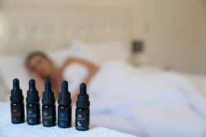 a woman laying in bed with five bottles of cbd