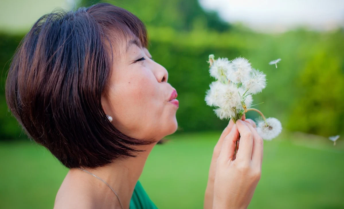 woman blowing dandelion