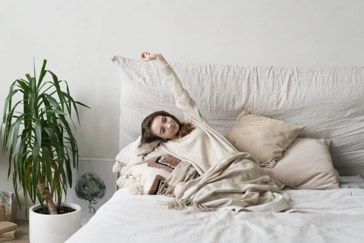 a woman laying on a bed with a blanket