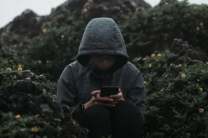 a person sitting on a rock looking at a cell phone