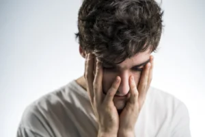 Sad man holding face with white shirt and black hair