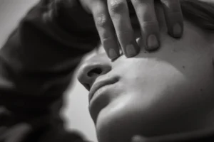 Close-up of a person's face with hand covering eye