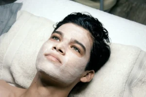 A man laying on a bed with a towel on his head